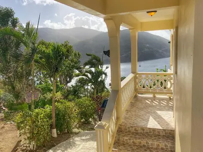 a house with a balcony with a view of the water at Ocean View Villas in Jost Van Dyke