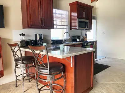 a kitchen with a counter and two bar stools at Ocean View Villas in Jost Van Dyke