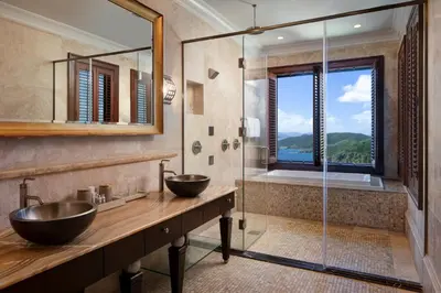 a bathroom with two sinks and a glass shower at Peter Island Resort in Anderson