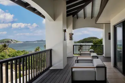 a balcony with chairs and a view of the ocean at Peter Island Resort in Anderson