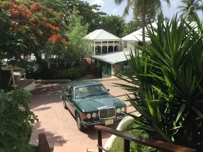 a green car parked in front of a house at Sugar Mill Hotel in Great Carrot Bay
