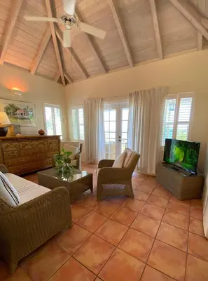 a living room with a couch and a tv at Sugar Mill Hotel in Great Carrot Bay