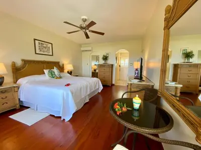 a large bedroom with a bed and a table at Sugar Mill Hotel in Great Carrot Bay