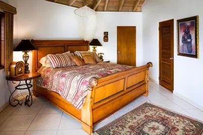 a bedroom with a large wooden bed and a table at TAMAR VILLA in Virgin Gorda