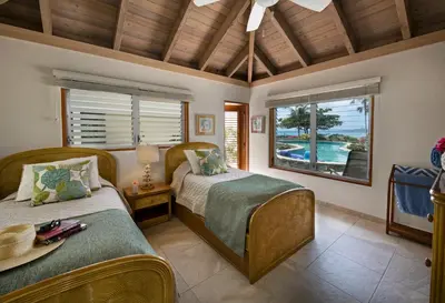 two beds in a room with a view of the ocean at BEACHCOMBER VILLA in Virgin Gorda
