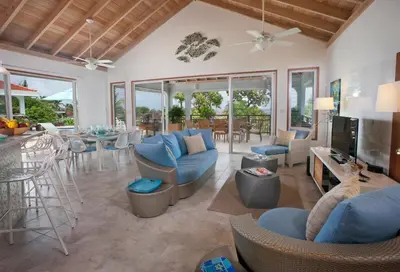 a living room with blue couches and chairs and a television at BLUE LAGOON in Virgin Gorda