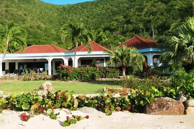 a house on the beach with a garden in front of it at BEACH DREAMS in Virgin Gorda