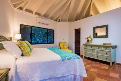 a bedroom with a bed and a dresser and a window at BEACH DREAMS in Virgin Gorda