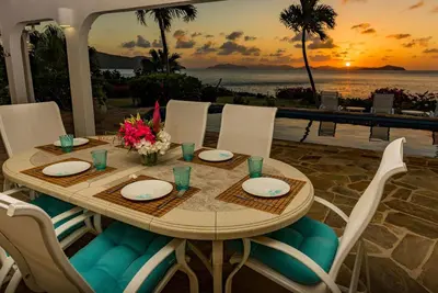 a table with plates and flowers on top of a patio at BEACH DREAMS in Virgin Gorda