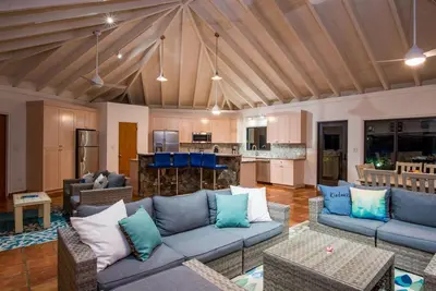 a living room with blue couches and a kitchen at BEACH DREAMS in Virgin Gorda