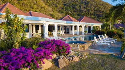 a house with a swimming pool and some purple flowers at BEACH DREAMS in Virgin Gorda