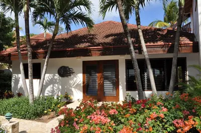 a house with palm trees and flowers in front of it at CARIBBEAN WIND in Virgin Gorda