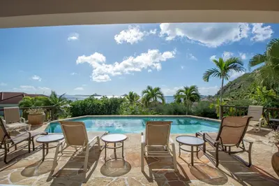 a swimming pool with chairs and a table next to a pool at LOBLOLLY in Virgin Gorda