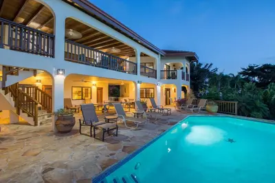 a house with a swimming pool in front of a house at LOBLOLLY in Virgin Gorda