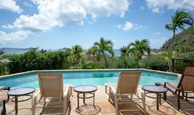 a swimming pool with chairs and a table next to a pool at LOBLOLLY in Virgin Gorda