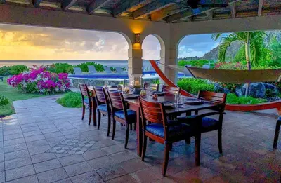 a table and chairs on a patio with a view of the ocean at SANDCASTLE in Virgin Gorda