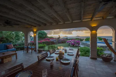a wooden table on a patio with a view of the ocean at SANDCASTLE in Virgin Gorda