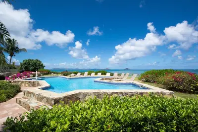 a swimming pool with a view of the ocean at SANDCASTLE in Virgin Gorda