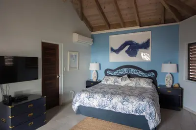 a bedroom with a bed and a blue wall at SANDCASTLE in Virgin Gorda