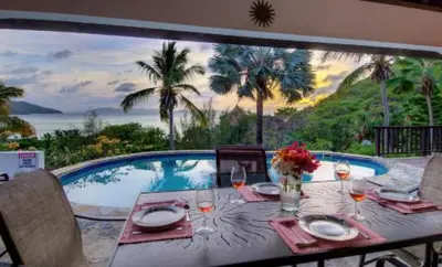 a table with wine glasses and a view of a pool at VILLA VALMARC in Virgin Gorda