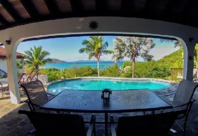 a table with chairs next to a swimming pool at VILLA VALMARC in Virgin Gorda