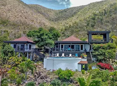 a house with a swimming pool in front of a mountain at VILLA DEL SOLE in Virgin Gorda