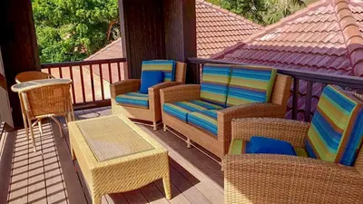 a porch with wicker chairs and a table at VILLA DEL SOLE in Virgin Gorda