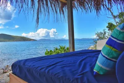 a bed on a beach with a view of the ocean at A DREAM COME TRUE VILLA in Virgin Gorda