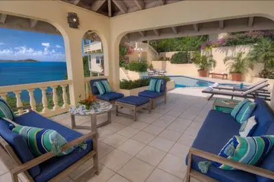 a patio with blue chairs and a swimming pool at A DREAM COME TRUE VILLA in Virgin Gorda