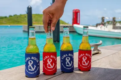 three bottles of beer on a table near the water at Saba Rock Resort in Virgin Gorda