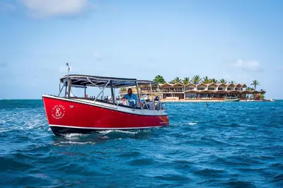 a red boat in the water in front of a resort at Saba Rock Resort in Virgin Gorda