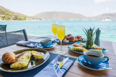 a table with two plates of breakfast food and drinks at Saba Rock Resort in Virgin Gorda