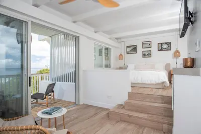 a living room with a bed and a balcony at Long Bay Beach Resort in Tortola Island