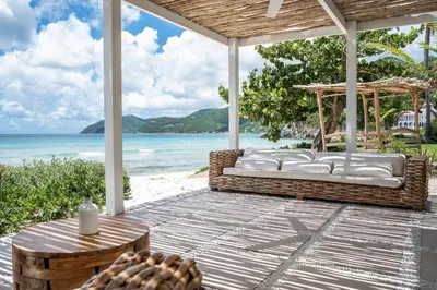 a porch with a couch and a table and the beach at Long Bay Beach Resort in Tortola Island