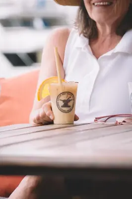 a woman sitting at a table holding a drink at Bitter End Yacht Club in Virgin Gorda