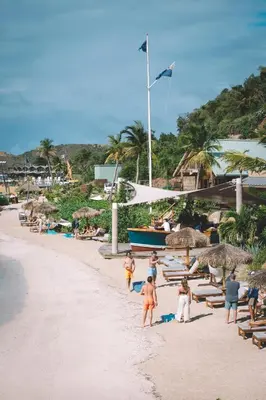 a group of people on a beach with chairs and umbrellas at Bitter End Yacht Club in Virgin Gorda