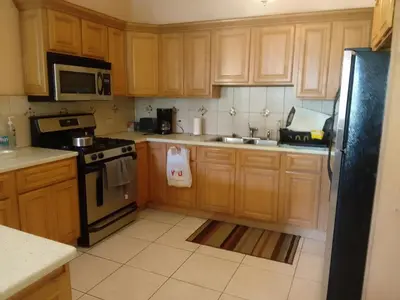 a kitchen with wooden cabinets and a black refrigerator at Abigail's Sunflower Entire 2 Bedroom Apt in Tortola Island