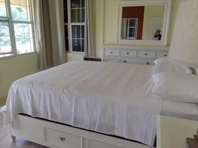 a white bedroom with a large white bed and a mirror at Abigail's Sunflower Entire 2 Bedroom Apt in Tortola Island