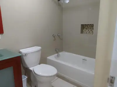 a white bathroom with a toilet and a bath tub at Abigail's Sunflower Entire 2 Bedroom Apt in Tortola Island